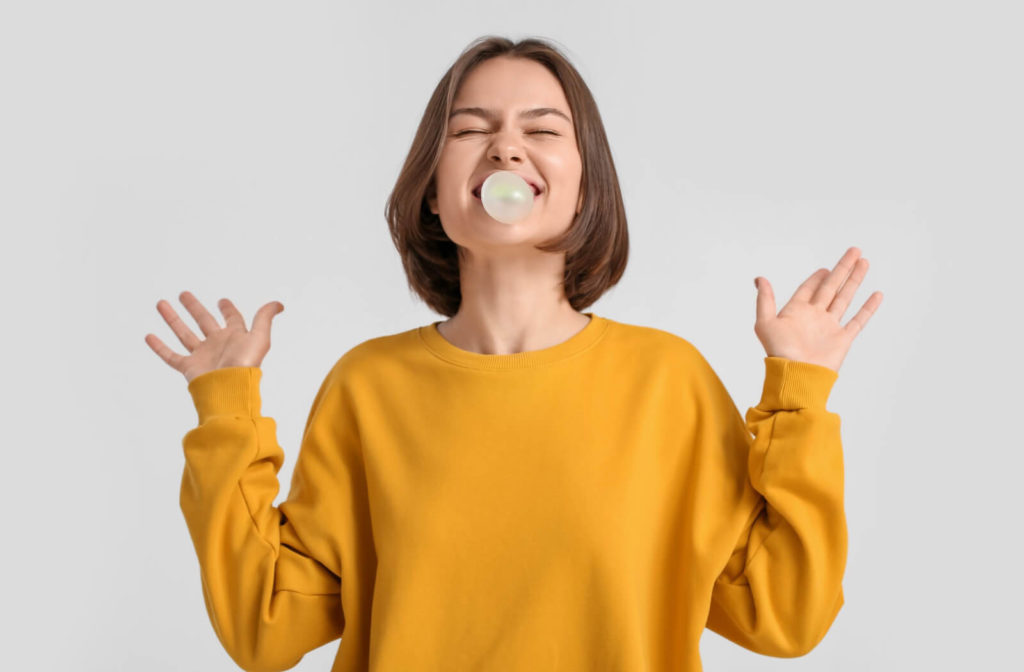 a woman blows a bubble with a piece of chewing gum